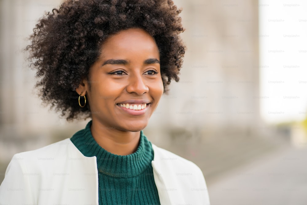 Retrato de mulher de negócios afro sorrindo enquanto está ao ar livre na rua. Conceito empresarial e urbano.