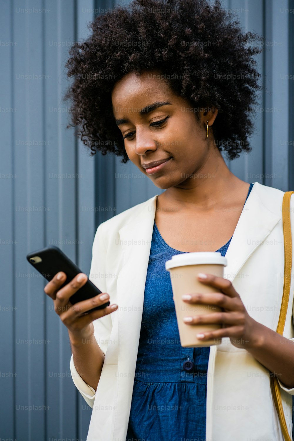 Ritratto di donna d'affari afro che usa il suo telefono cellulare mentre si trova all'aperto in strada. Concetto di business e urbano.