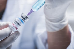COVID-19との戦い、実験室でのコロナウイルスワクチン研究、プロの科学者がウイルス治療注射用の注射器とボトルワクチンを保持し、パンデミック中の医療