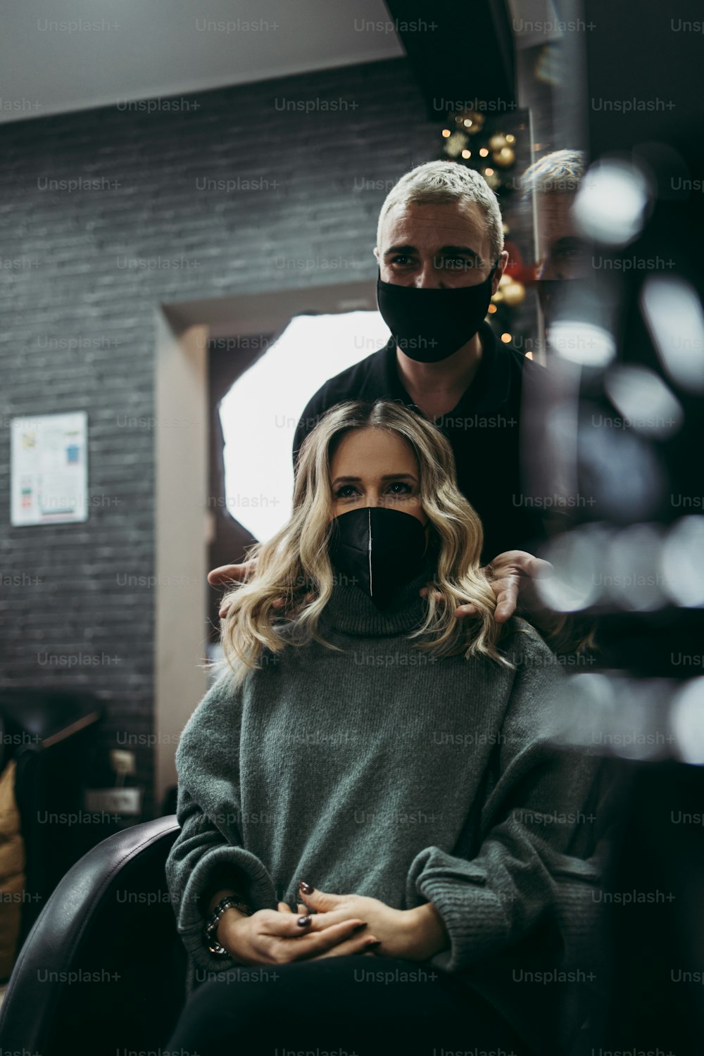 Hermoso peinado de mujer después de teñir el cabello y hacer reflejos en la peluquería. Lleva una mascarilla protectora como protección contra la pandemia del virus.