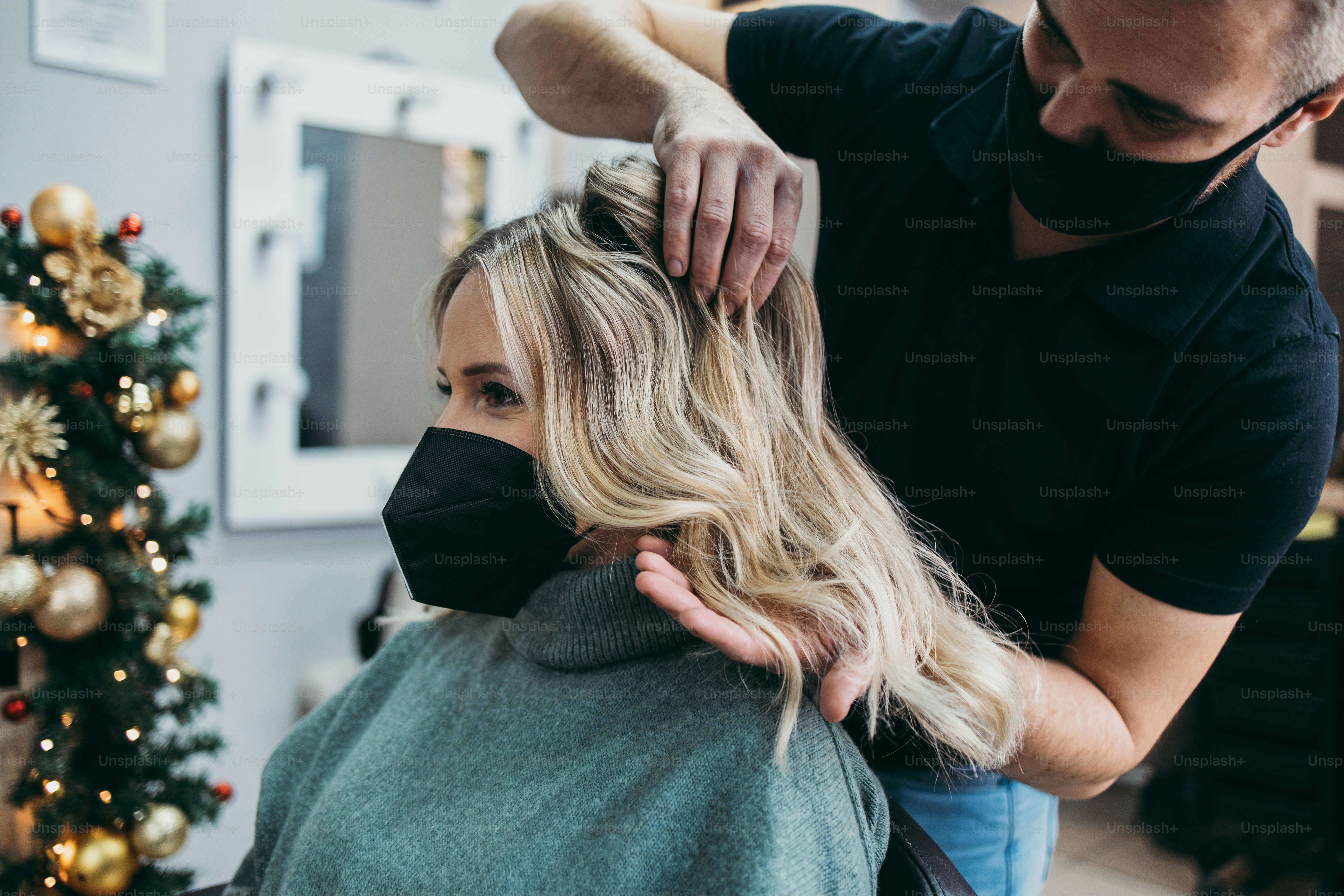 Hermoso peinado de mujer después de teñir el cabello y hacer reflejos en la peluquería. Lleva una mascarilla protectora como protección contra la pandemia del virus.