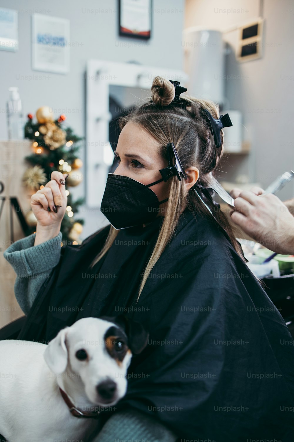 미용사는 여성의 머리카락을 염색하고 호일로 고객에게 머리카락 하이라이트를 만들고 있습니다. 그들은 바이러스 전염병으로부터 보호하기 위해 보호용 안면 마스크를 착용하고 있습니다.