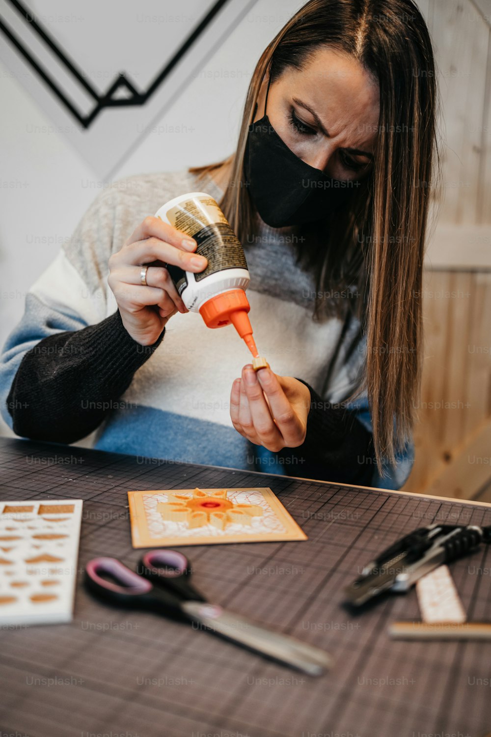 Papierkunstdesignerin und Künstlerin bei der Arbeit in ihrem Atelier oder ihrer Werkstatt. Sie trägt eine Schutzmaske gegen die Viruspandemie.