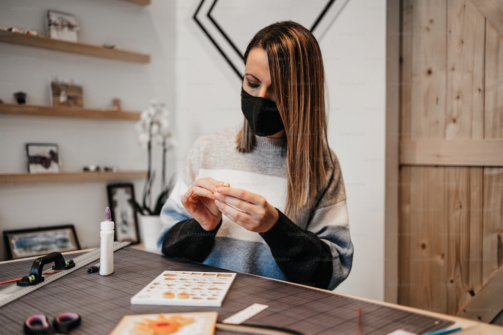 Paper art designer and artist working in her studio or workshop. She is wearing protective face mask against virus pandemic.