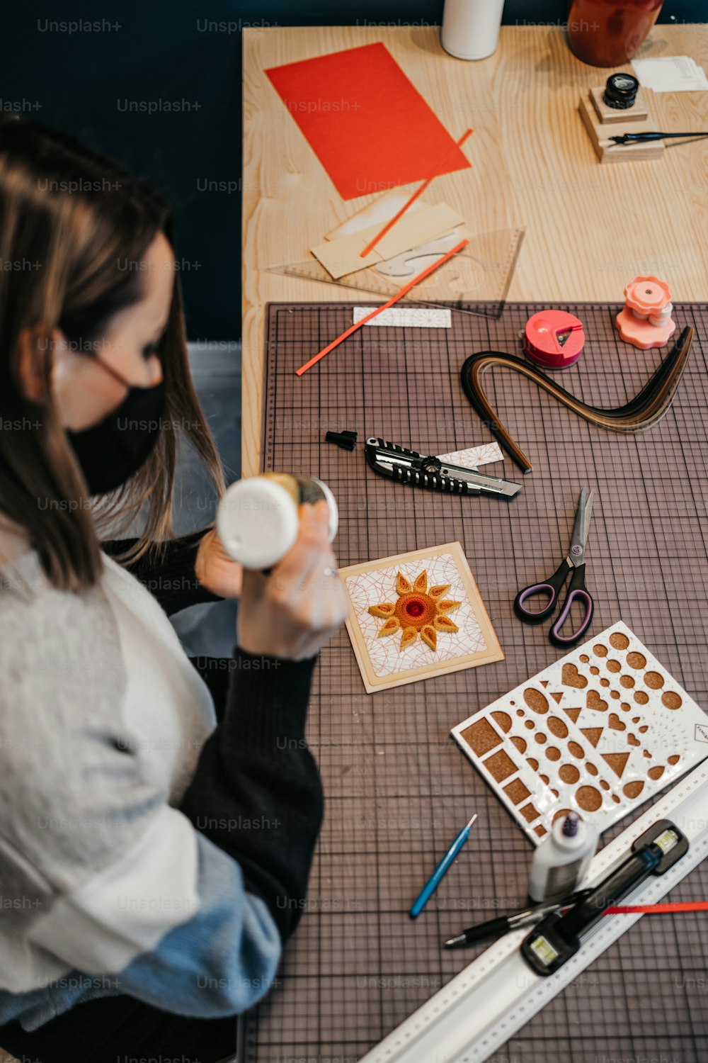 Diseñadora de arte en papel y artista que trabaja en su estudio o taller. Lleva una mascarilla protectora contra la pandemia del virus.