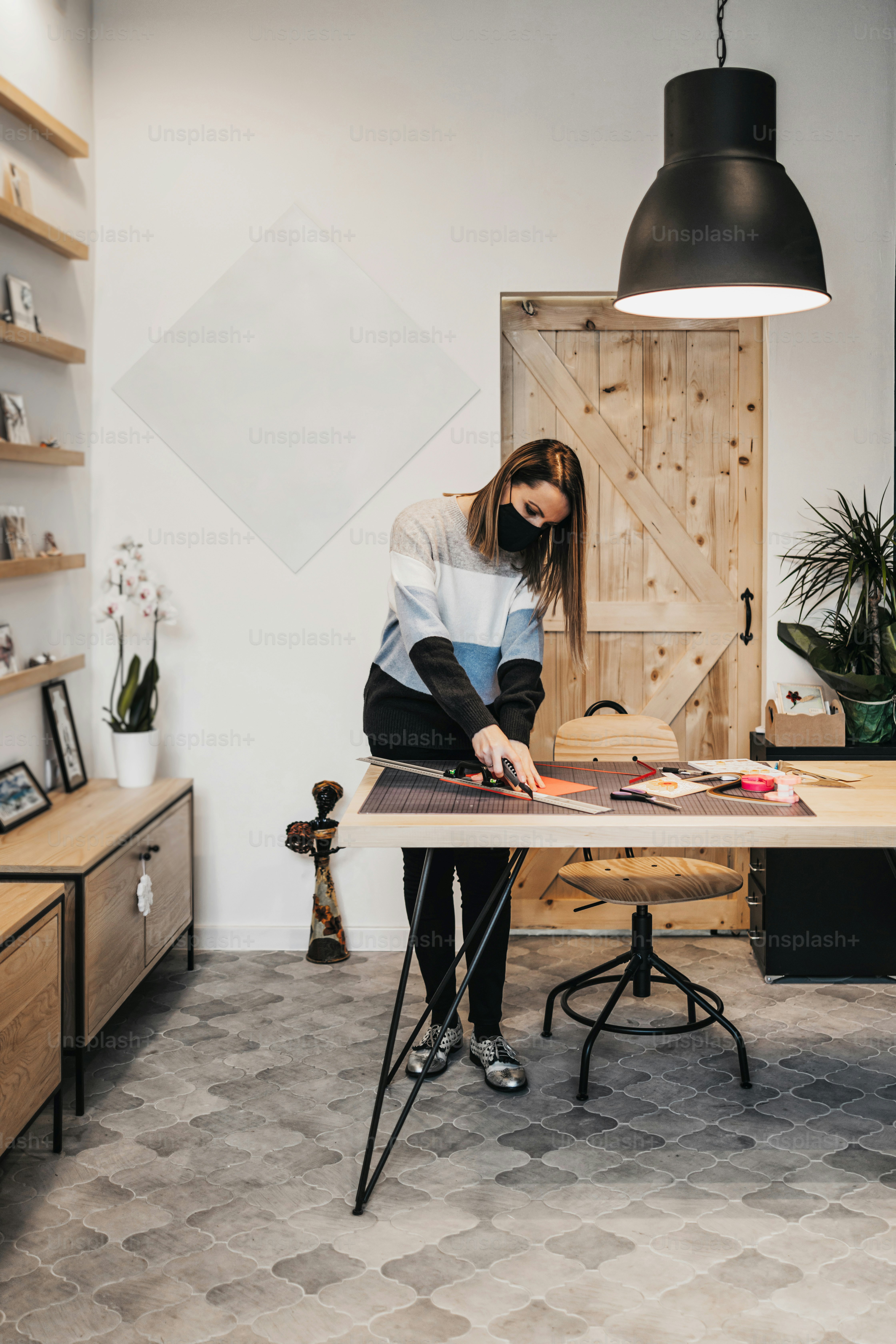 Diseñadora de arte en papel y artista que trabaja en su estudio o taller. Lleva una mascarilla protectora contra la pandemia del virus.