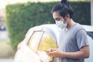 Asia man wearing a medical mask and using a phone outdoors