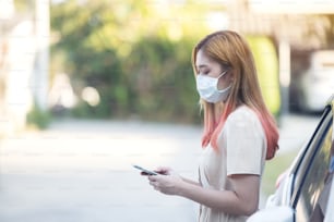 Asia woman wearing a medical mask and using a phone outdoors