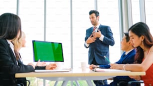 Uomini d'affari nella sala conferenze con schermo verde chroma key TV o computer sul tavolo dell'ufficio. Gruppo eterogeneo di uomo d'affari e donna d'affari in riunione in videoconferenza.