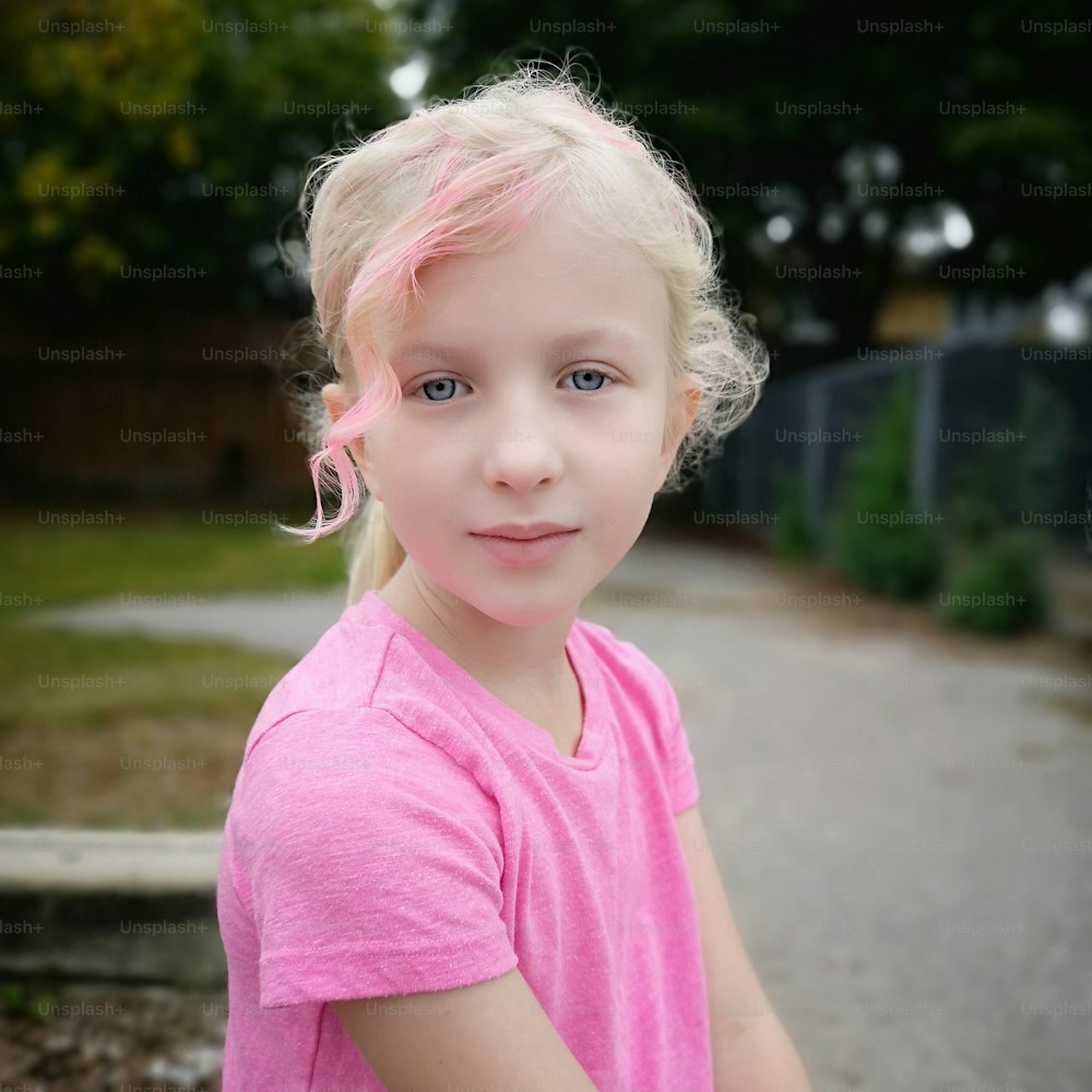 Mignonne adorable fille d’école primaire avec une frange colorée en rose. Adorable jolie fille blonde caucasienne aux cheveux toniques de couleur vive en plein air. Cool élégant fantaisie hipster enfant.