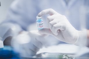 COVID-19との戦い、病院の実験室でのコロナウイルスワクチン研究、プロの科学者がウイルス治療注射用の新しいワクチンのボトルを保持し、パンデミック中の医療