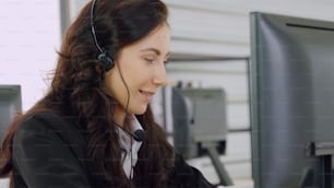 Personas de negocios que usan auriculares que trabajan en la oficina para apoyar a clientes o colegas remotos. El centro de llamadas, el telemarketing y el agente de atención al cliente brindan servicio en llamadas telefónicas de videoconferencia.