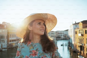 mulher turista da moda em vestido floral com chapéu tendo passeio a pé na ponte Accademia em Veneza, Itália.