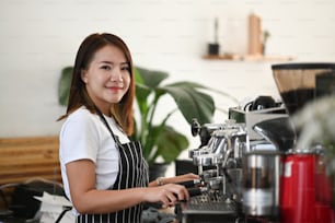 Barista asiática feminina preparando xícara de café para o pedido do cliente na cafeteria.