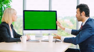 Des gens d’affaires dans la salle de conférence avec écran vert, une télévision à clé chromatique ou un ordinateur sur la table du bureau. Groupe diversifié d’hommes et de femmes d’affaires en réunion par vidéoconférence.