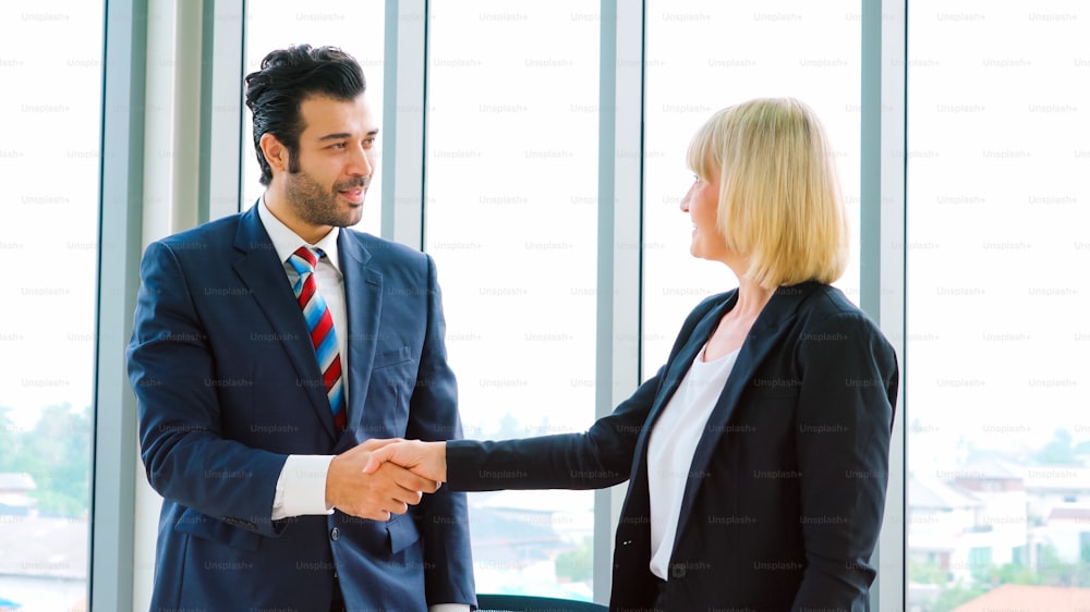 Business people handshake in corporate office showing professional agreement on a financial deal contract.