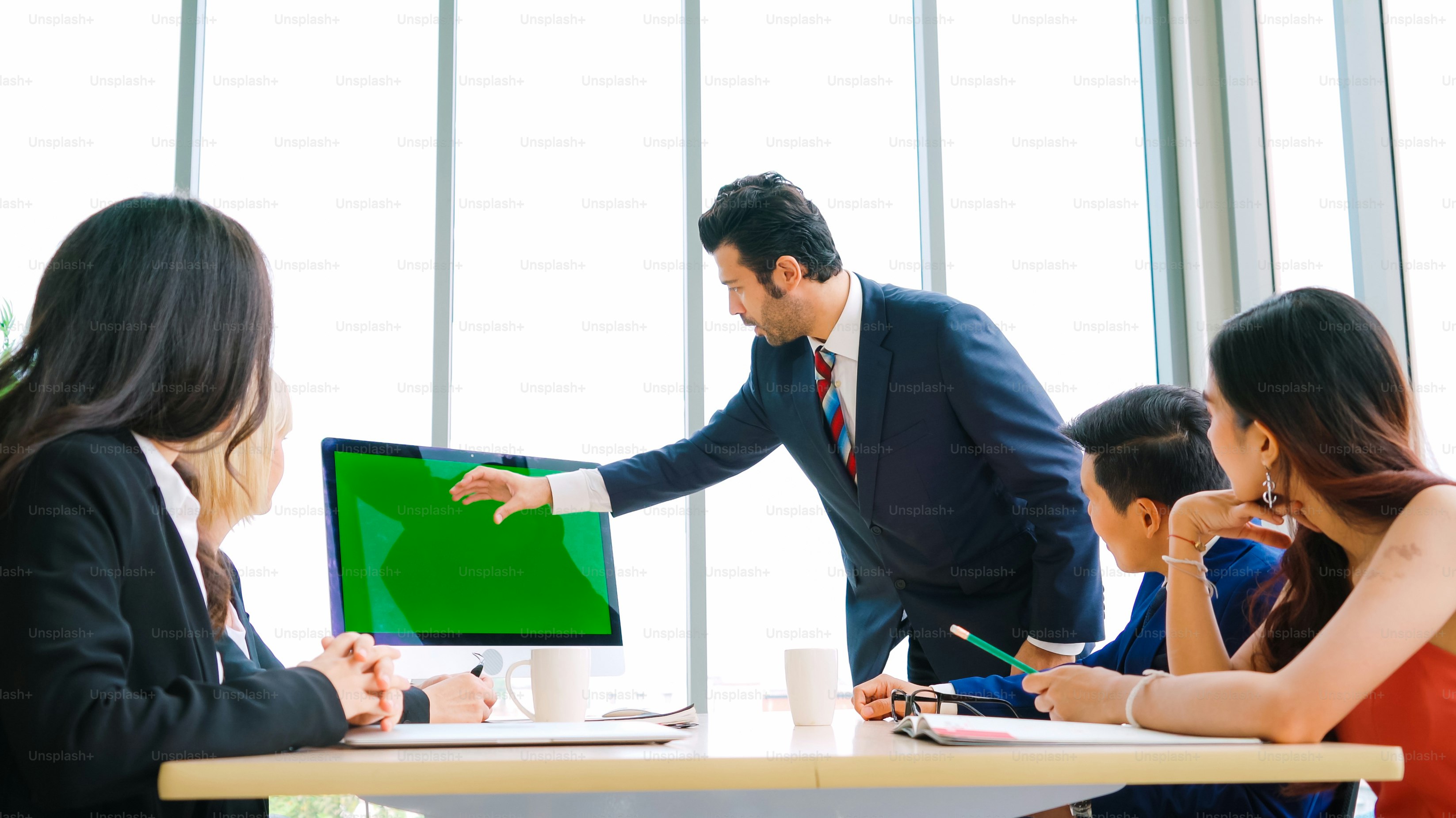 Business people in the conference room with green screen chroma key TV or computer on the office table. Diverse group of businessman and businesswoman in meeting on video conference call .