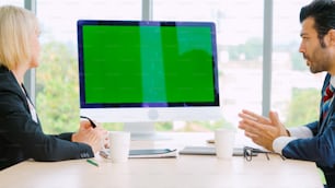 オフィスのテーブルにグリーン スクリーン クロマ キー テレビまたはコンピューターを備えた会議室のビジネスマン。ビデオ会議通話で会議を行うビジネスマンとビジネスウーマンの多様なグループ。