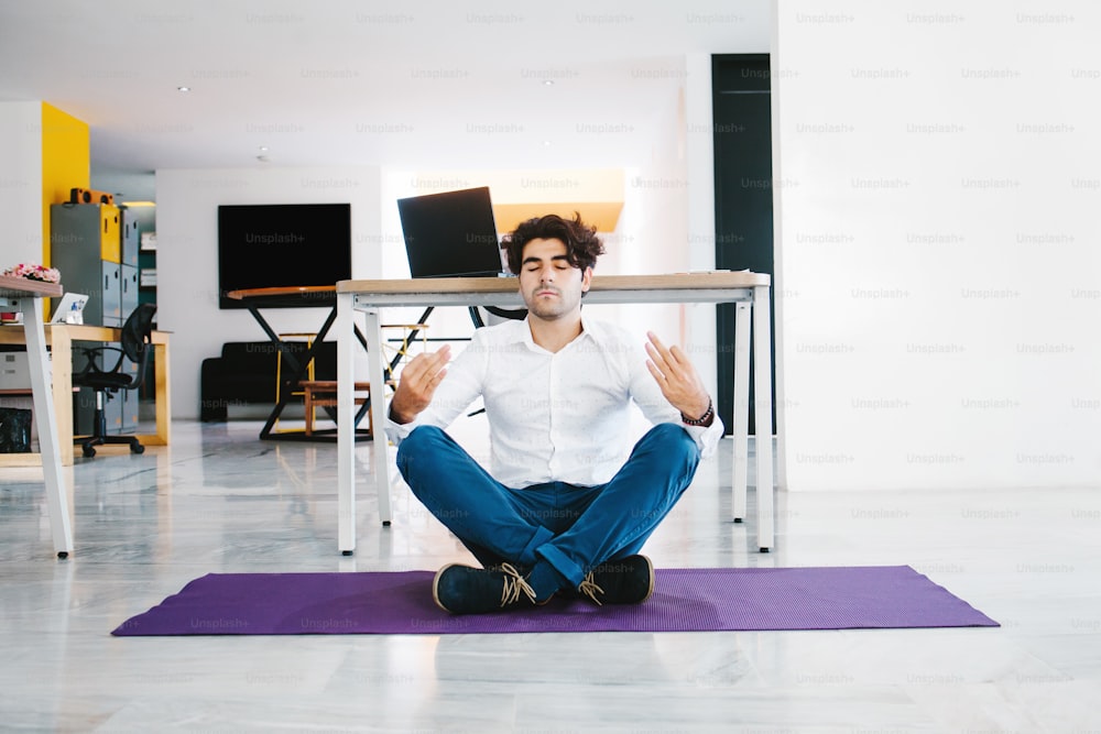 Joven mexicano meditando y haciendo yoga en oficina en América Latina