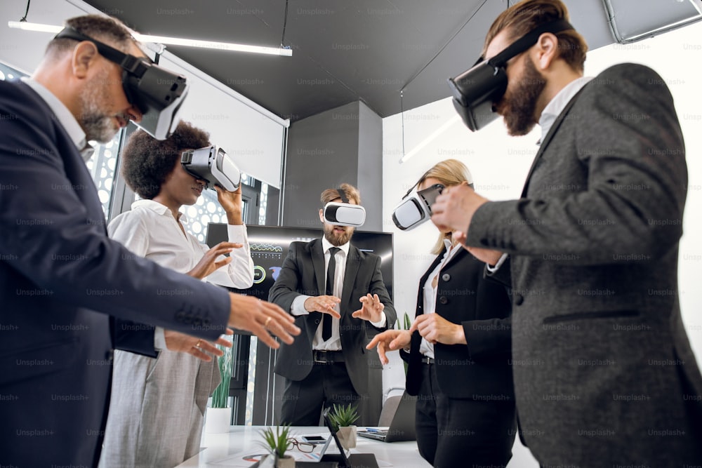 Grupo de cinco pessoas multiétnicas que trabalham com óculos de realidade virtual em escritório moderno. Nova tecnologia, visualização 3D, startup, futuro, arquitetura e conceito de design.