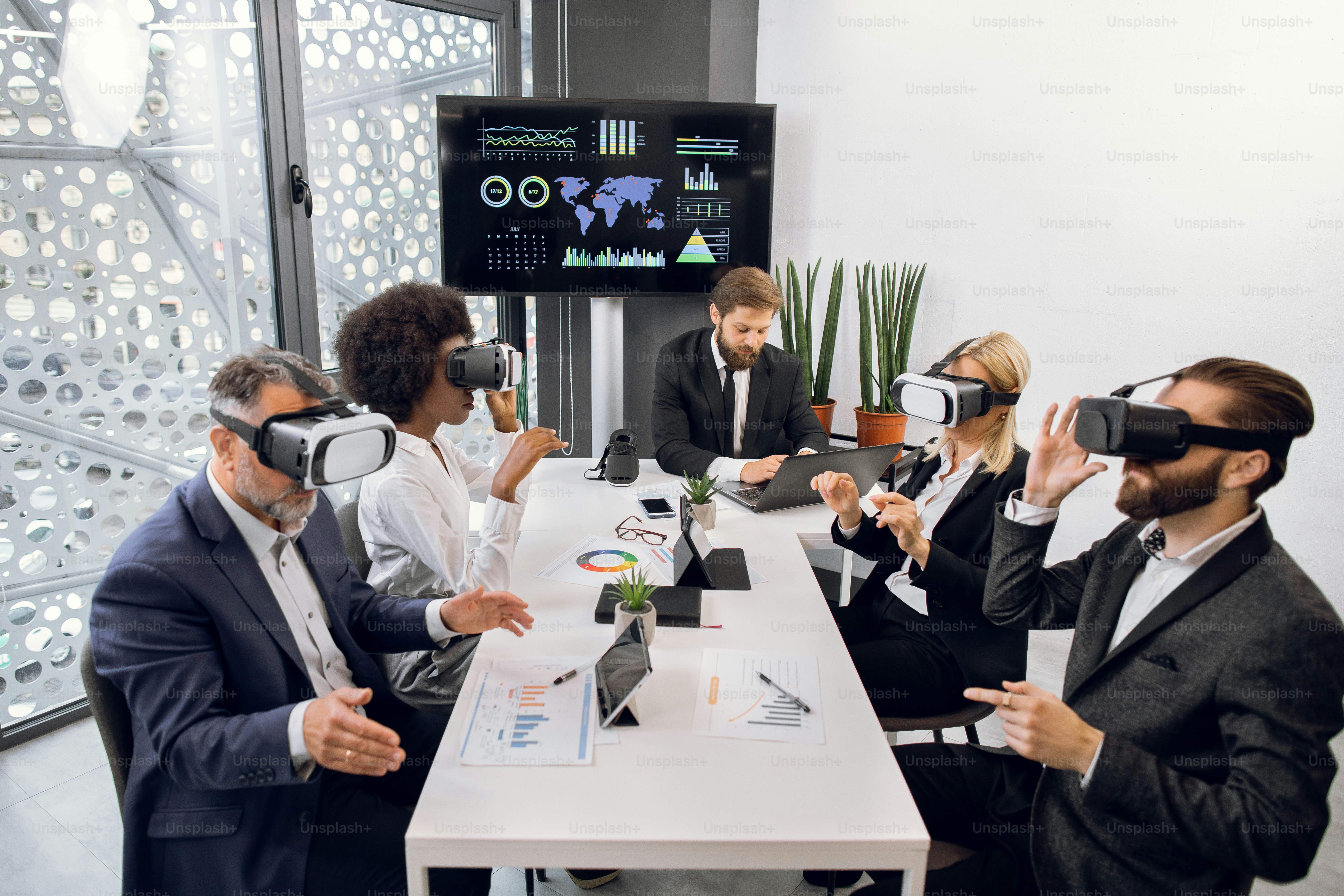 Equipo de negocios que trabaja en gafas de realidad virtual. Jefe masculino que trabaja en una computadora portátil en la oficina, mientras que su equipo multiétnico trabaja con gafas de realidad virtual y desarrolla un proyecto
