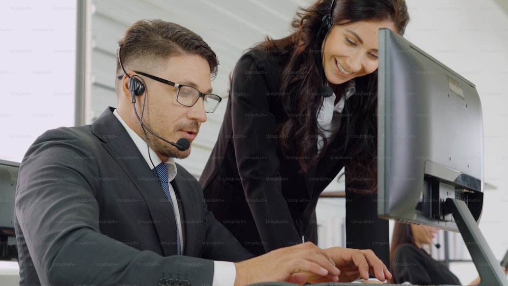 ヘッドセットを装着したビジネスマンがオフィスで作業し、リモートの顧客や同僚をサポートします。コールセンター、テレマーケティング、カスタマーサポートエージェントは、電話ビデオ会議通話でサービスを提供します。