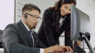 Personas de negocios que usan auriculares que trabajan en la oficina para apoyar a clientes o colegas remotos. El centro de llamadas, el telemarketing y el agente de atención al cliente brindan servicio en llamadas telefónicas de videoconferencia.