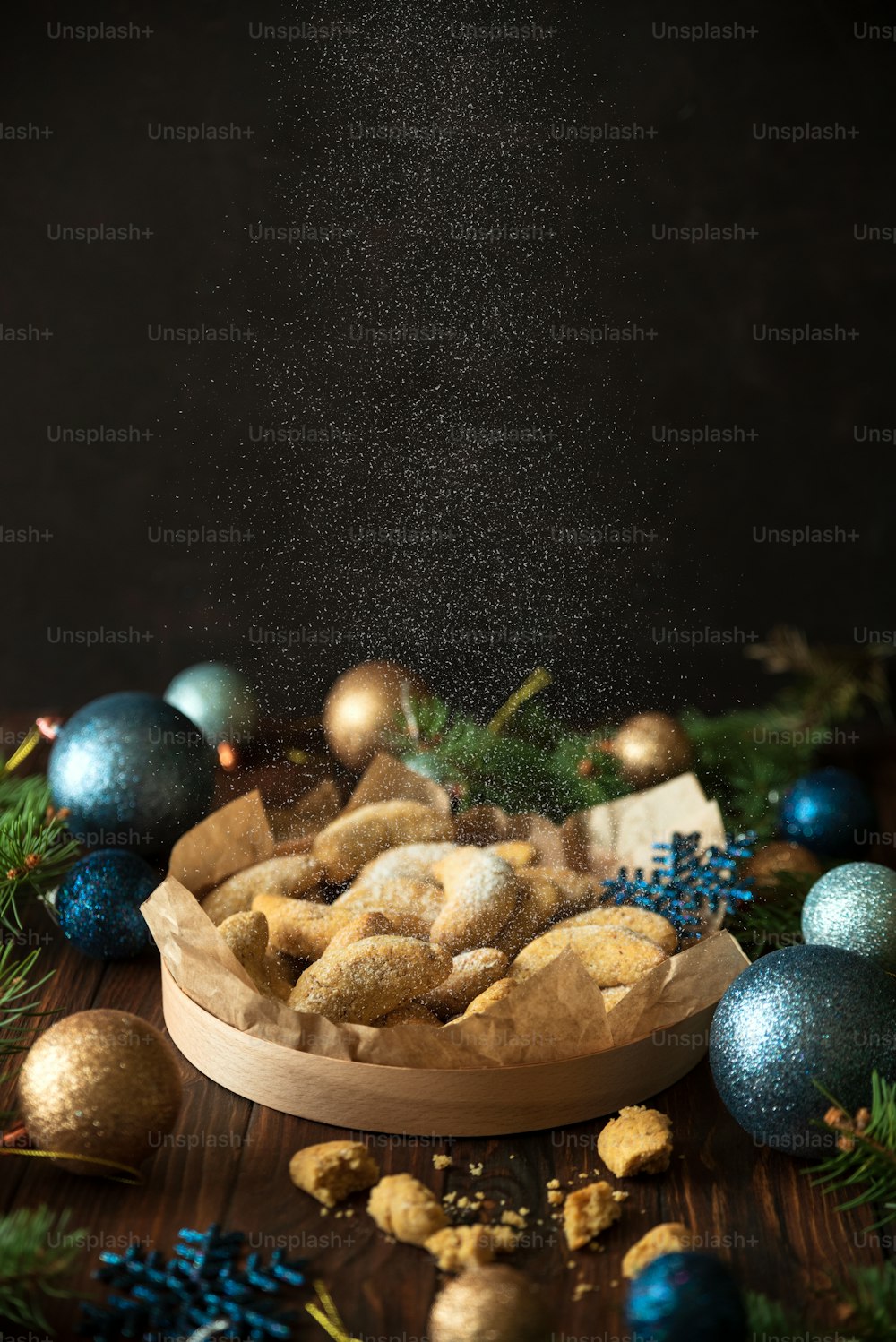 Homemade Christmas nuts cookies vanilla crescent with sugar powder in Christmas decorations. New Year and Christmas celebration concept. Copy space. Soft focus. Flying sugar powder