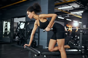 Serious brunette woman looking forward while doing her best for strong muscles