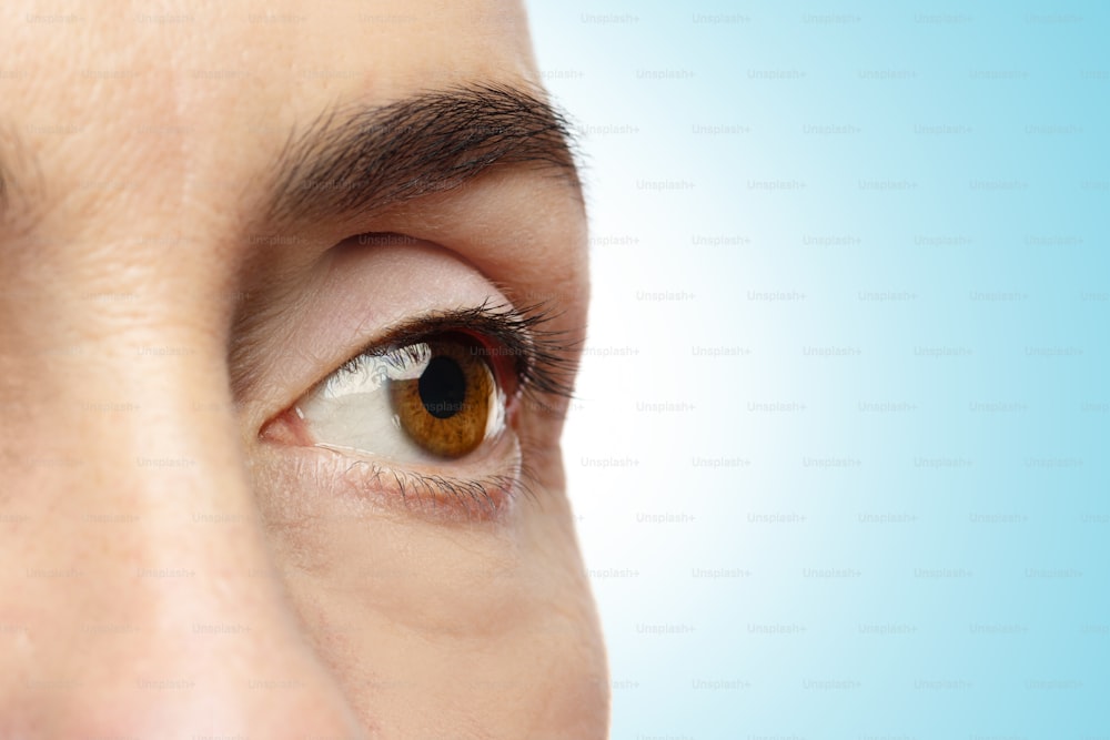 Close-up of female eye on blue background. Rejuvenation or Ophthalmology concepts.