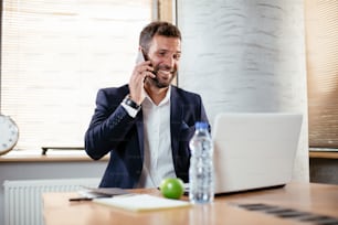 Smiling businessman talking to the phone. Young man using the phone in the office.