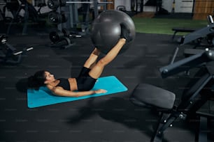 Kind female person using fitness ball while doing ABS exercises