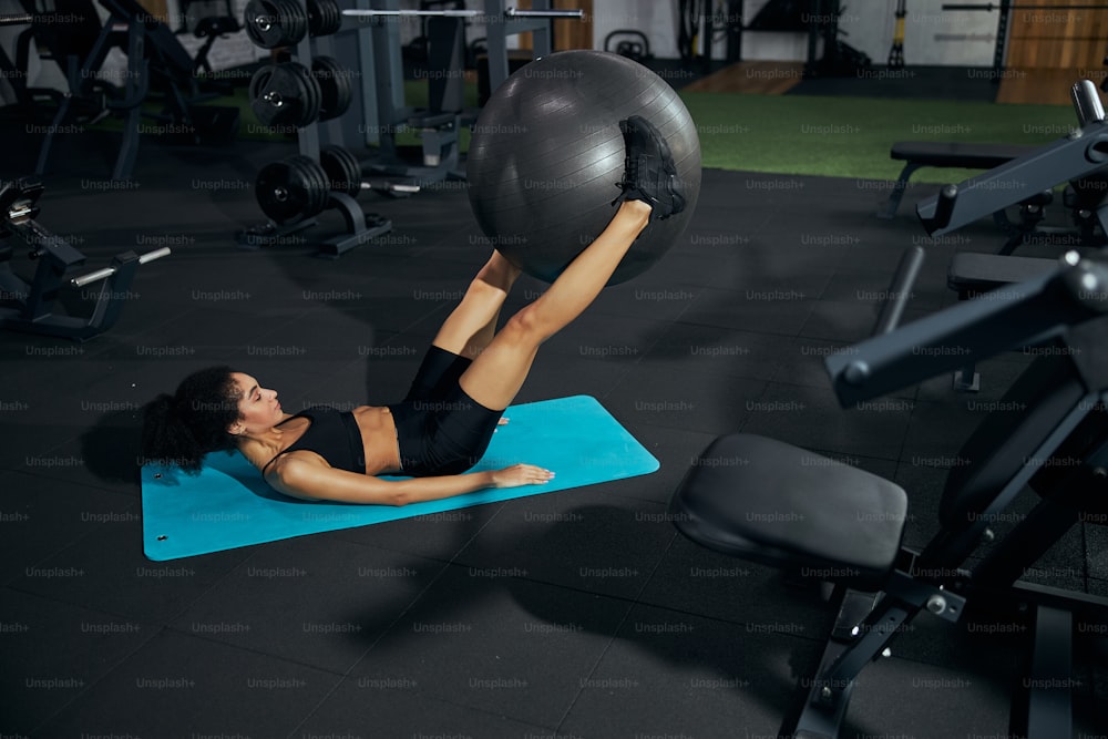 Kind female person using fitness ball while doing ABS exercises