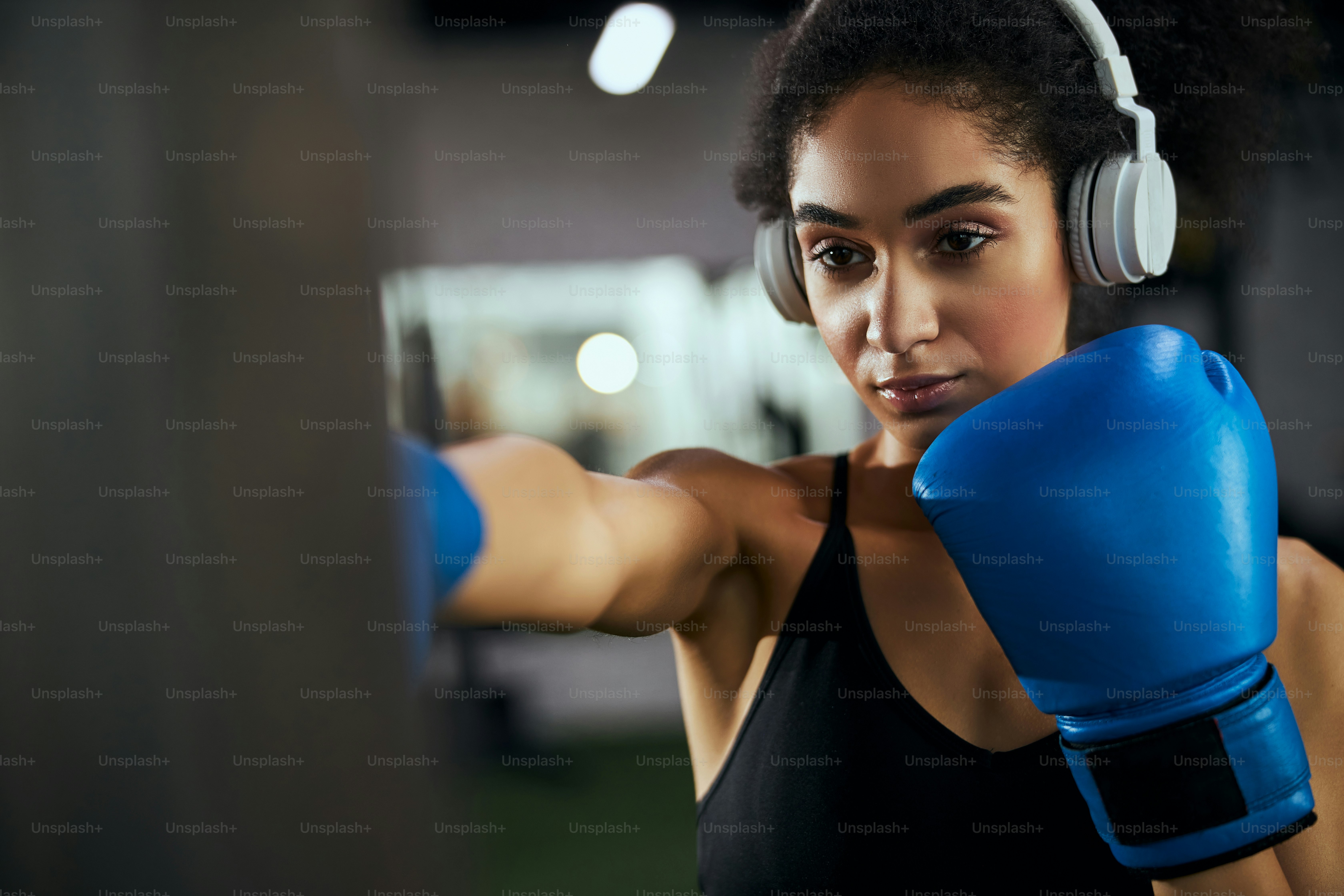 Wanita muda yang serius memakai headphone saat mendengarkan musik selama pelatihan