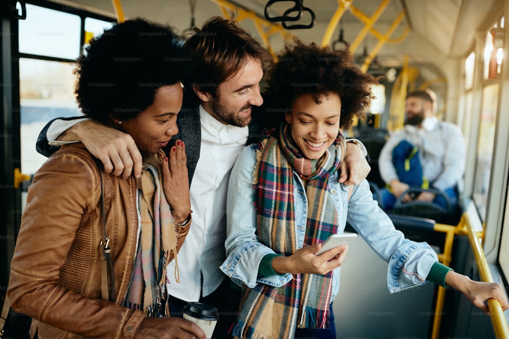 Grupo de amigos felices usando el teléfono móvil y divirtiéndose mientras viajan en autobús.