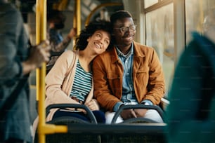 대중 교통으로 통근하는 동안 창문을 통해 보고 있는 행복한 흑인 커플.