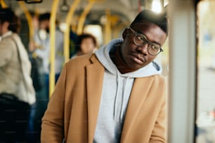 Young African American man looking through the window and thinking of something while traveling by bus.