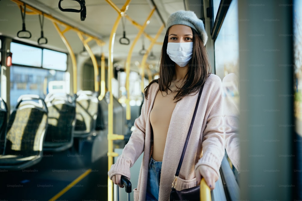 Giovane donna che si sposta in autobus e indossa la mascherina a causa della pandemia di coronavirus.