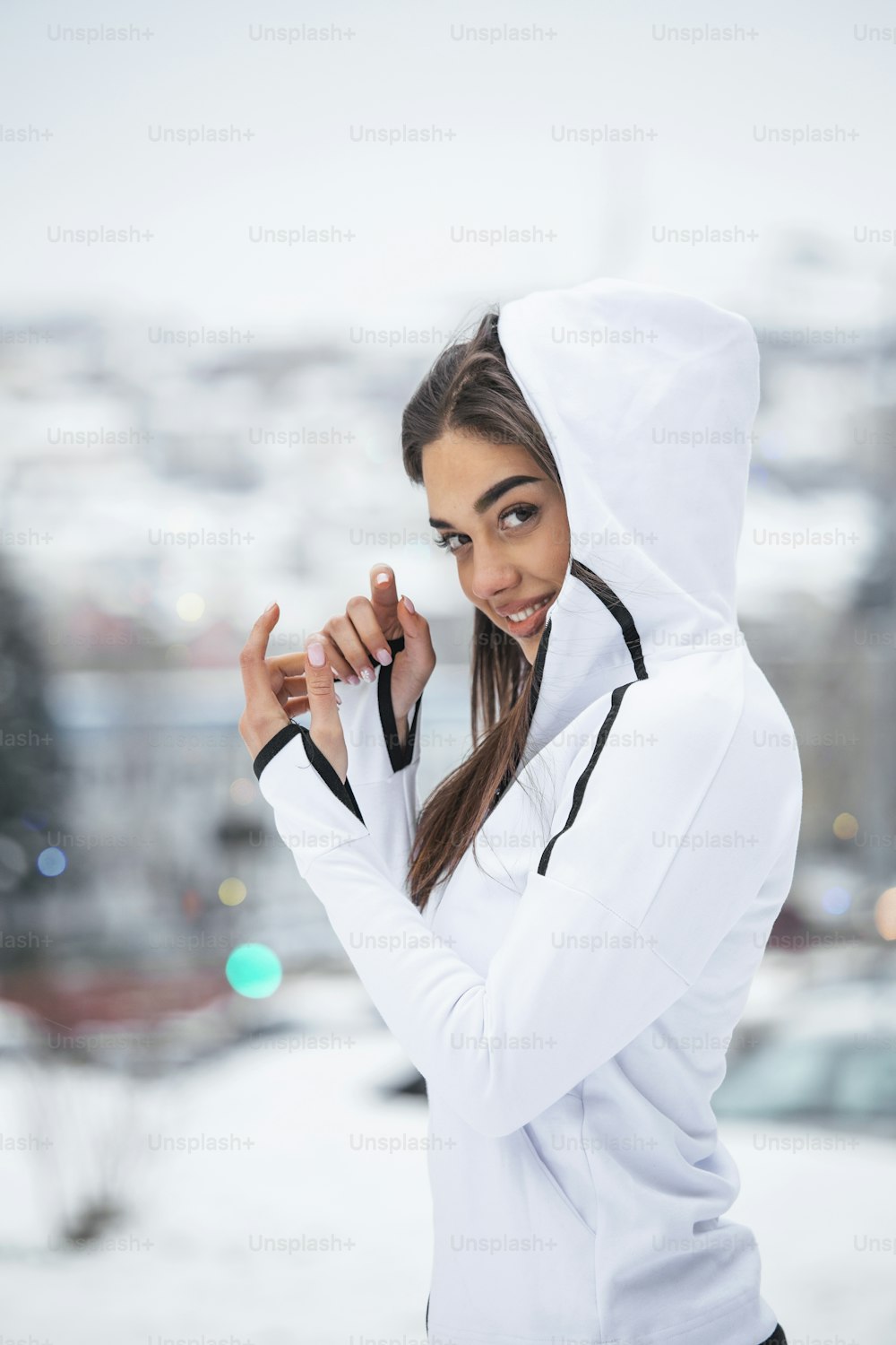 Vista de retrato de joven, satisfecha, sonriente, motivada y enfocada, chica deportiva activa calentándose en ropa deportiva de invierno, la naturaleza nevada por la mañana.