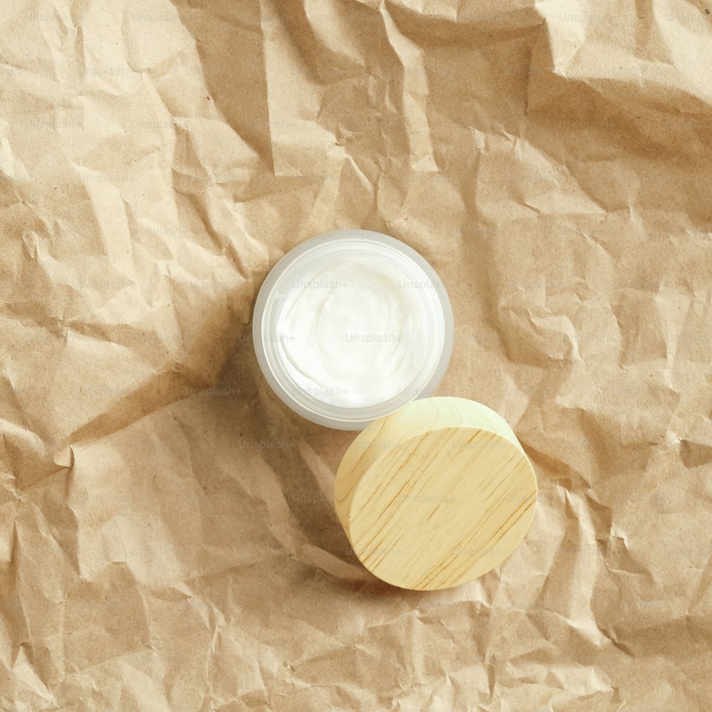 Vasetto di crema viso idratante naturale su carta kraft vista dall'alto. Confezione di prodotti di bellezza ecologici
