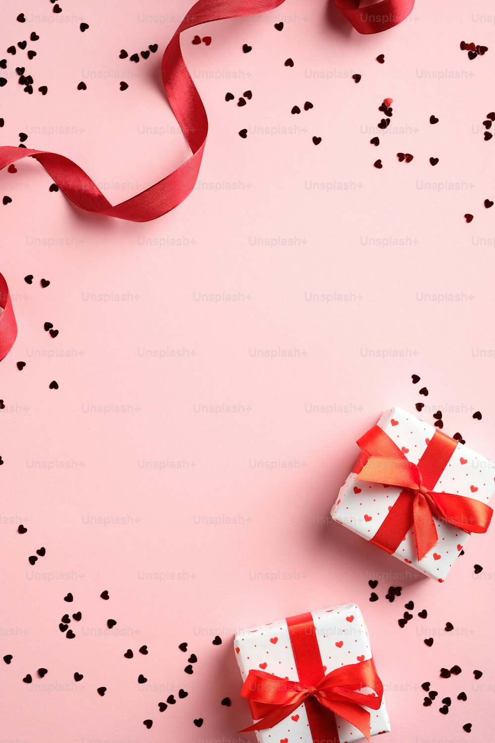 Valentines day card template with gifts, red ribbon, confetti on pink background. Flat lay, top view, copy space.