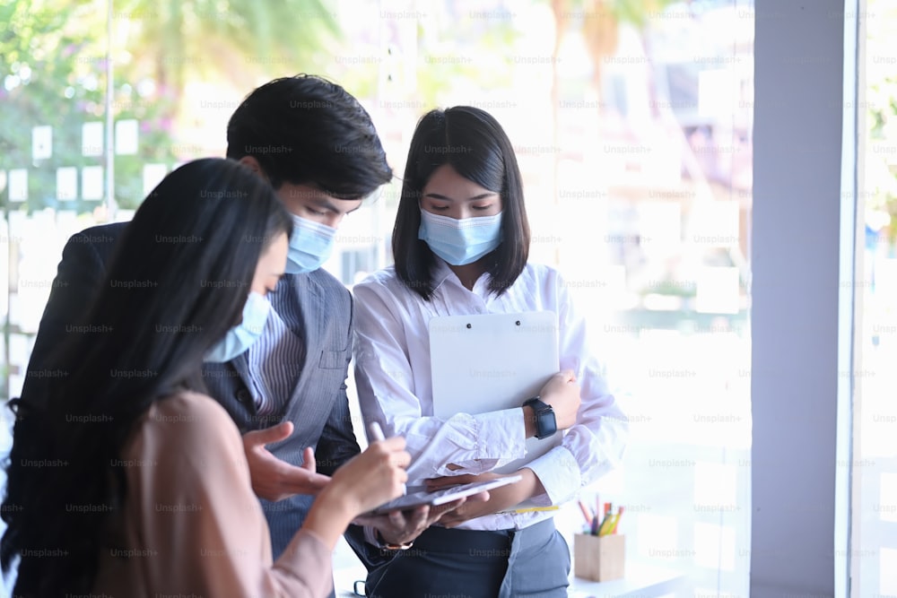 Group of business people in protective mask working and communicating while meeting at office.