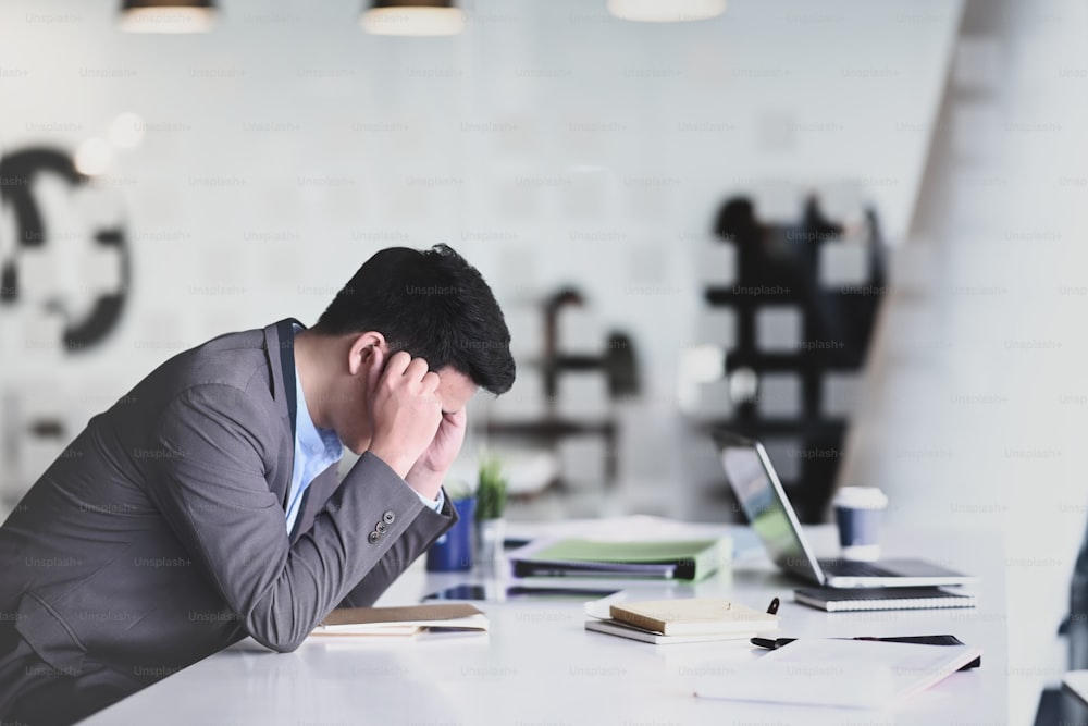 Vue latérale : homme d’affaires frustré, se sentant stressé et contrarié alors qu’il est assis au bureau.
