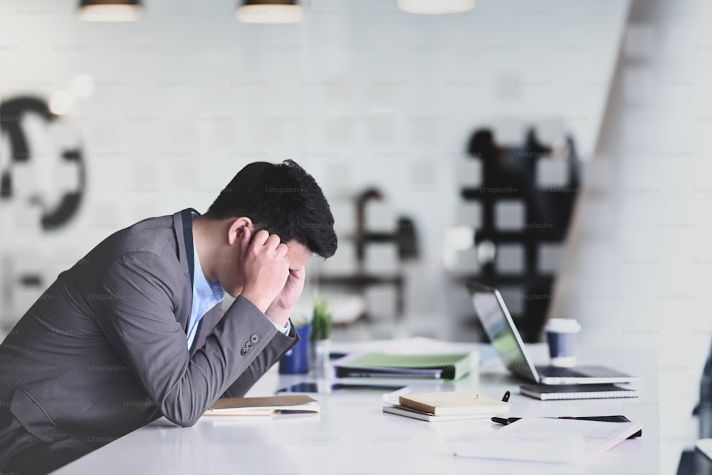 Side view frustrated businessman feeling stressed and upset while sitting at office.