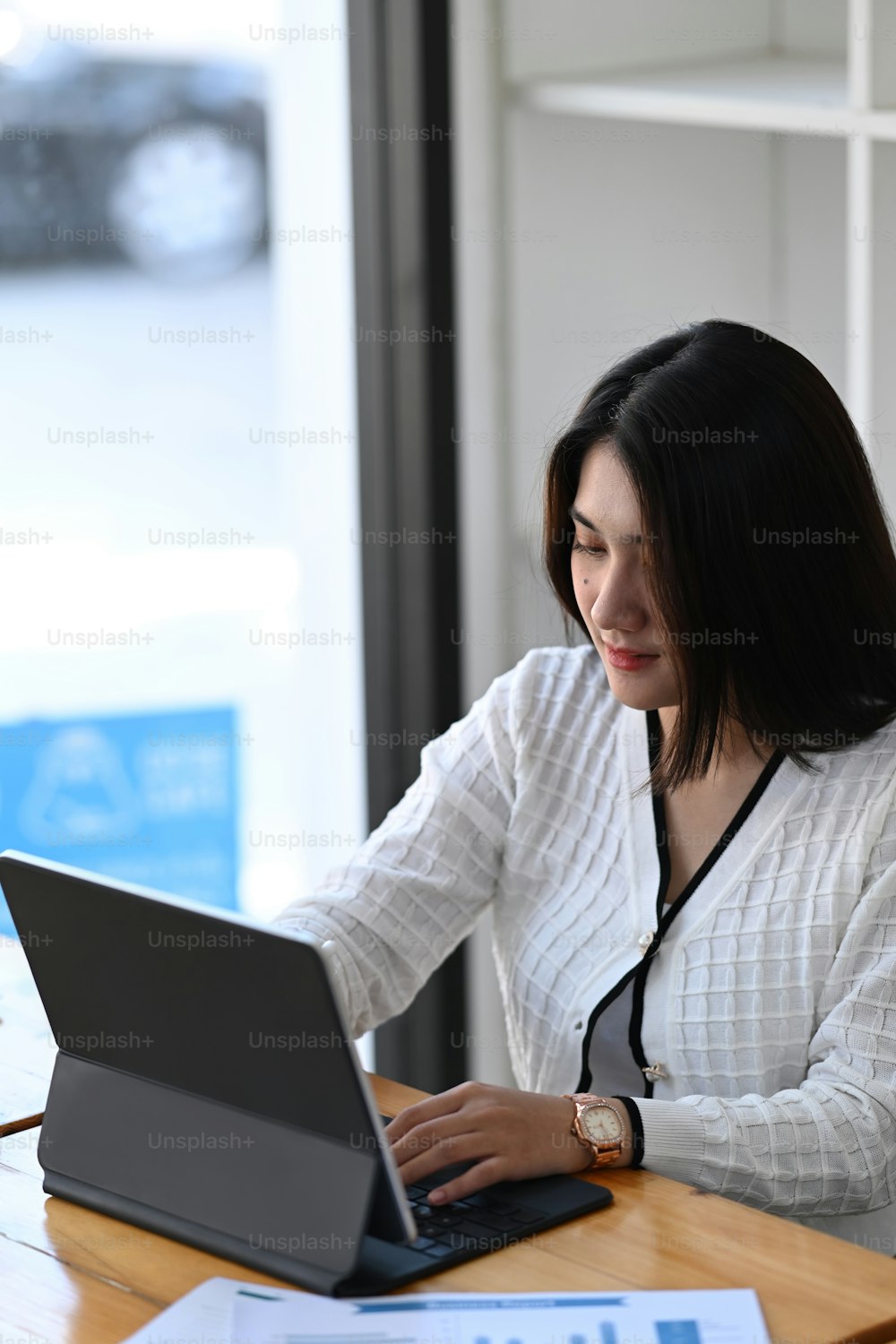 Businesswoman working on tablet computer and making report financial planning report at office desk.