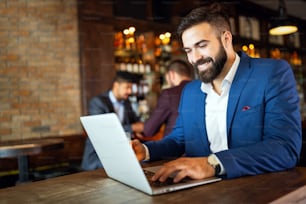 Portrait of a successful entrepreneur man sitting at the cafe working on a laptop.