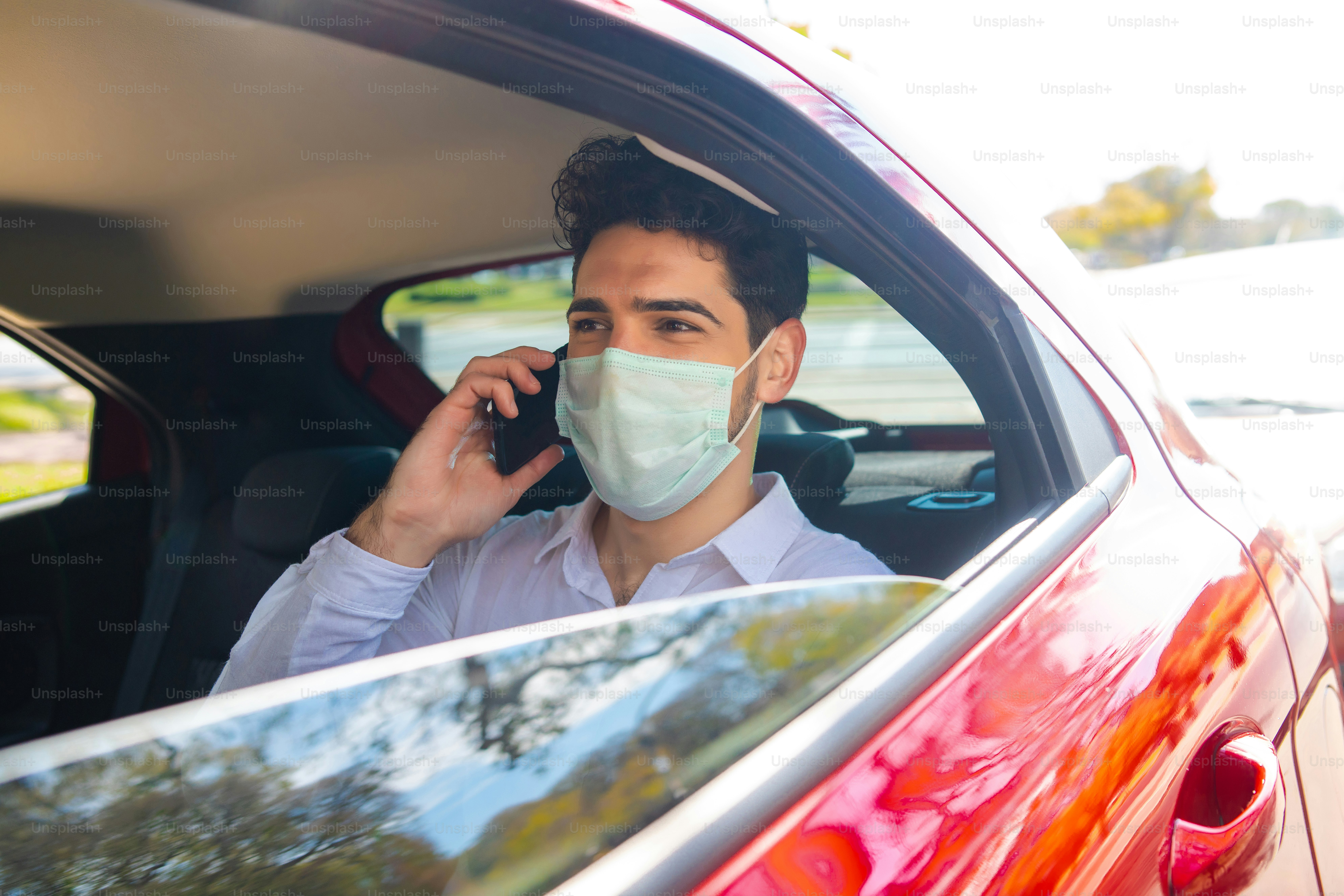 Portrait d’un homme d’affaires portant un masque facial et parlant au téléphone sur le chemin du travail dans une voiture. Concept d’entreprise. Nouveau concept de mode de vie normal.