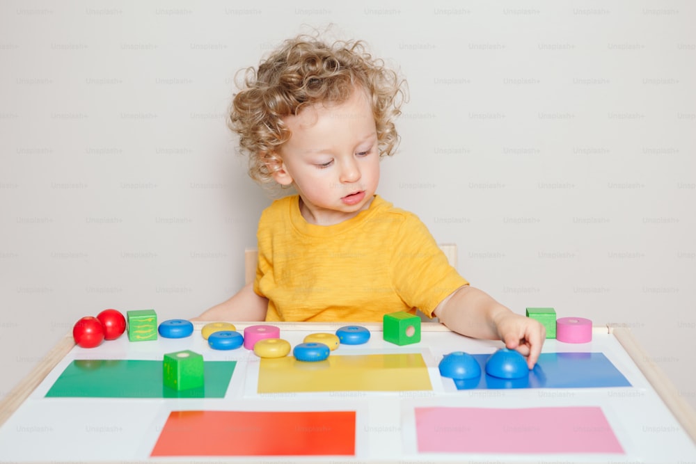 Tout-petit jouant avec des jouets d’apprentissage à la maison ou à la maternelle. Tri de bébé, organisation d’objets : blocs de couleurs spécifiques. Éducation préscolaire. Activité de développement du cerveau de la main pour les enfants d’âge préscolaire.