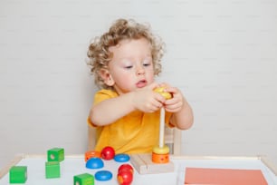 집이나 유치원에서 장난감 피라미드 쌓기 블록을 배우고 노는 귀여운 아기 유아. 조기 교육. 미취학 아동을 위한 아이들의 손 두뇌 재미있는 발달 활동.