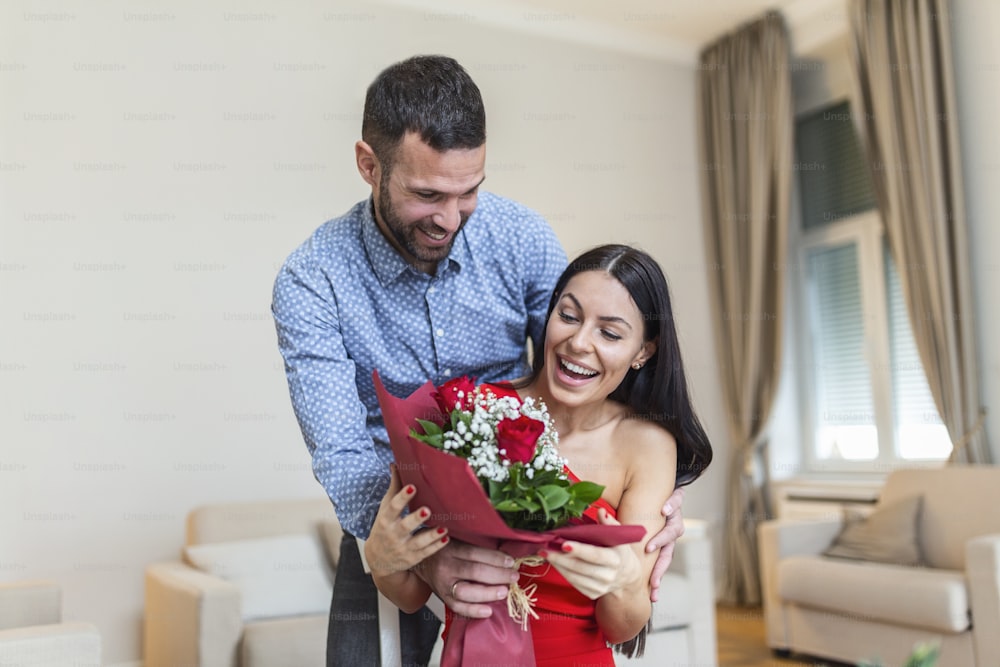 Beau couple heureux, positif s’embrassant, tenant un bouquet de roses rouges, 14 février joyeuse Saint-Valentin